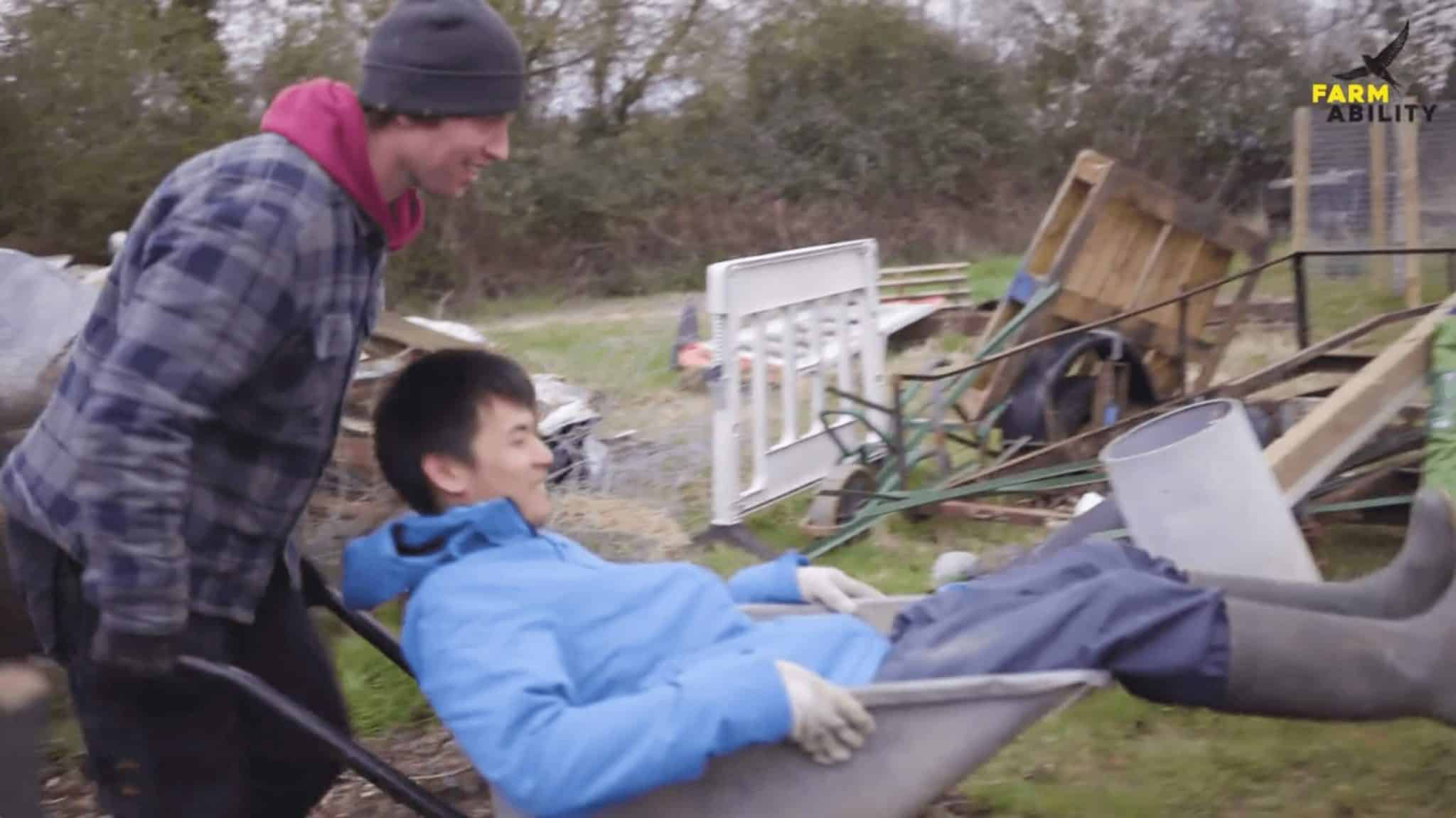one person pushing another in a wheelbarrow