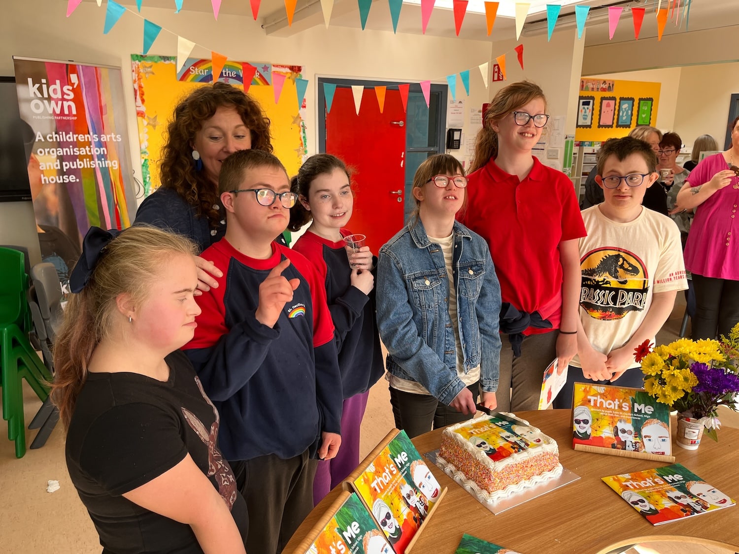 group of adults and children standing around a birthday cake