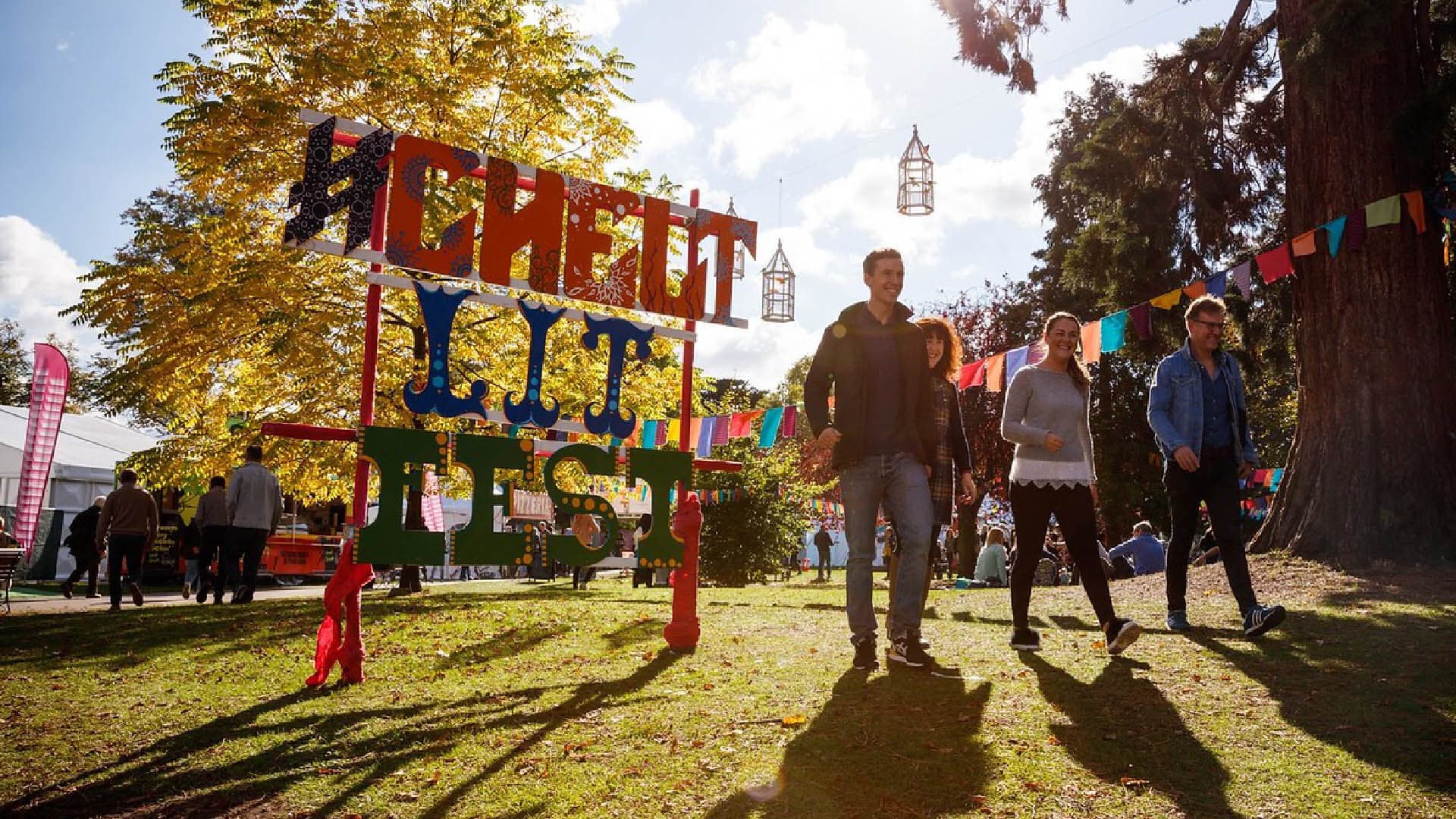 4 people walking past Cheltenham Literature Festival sign