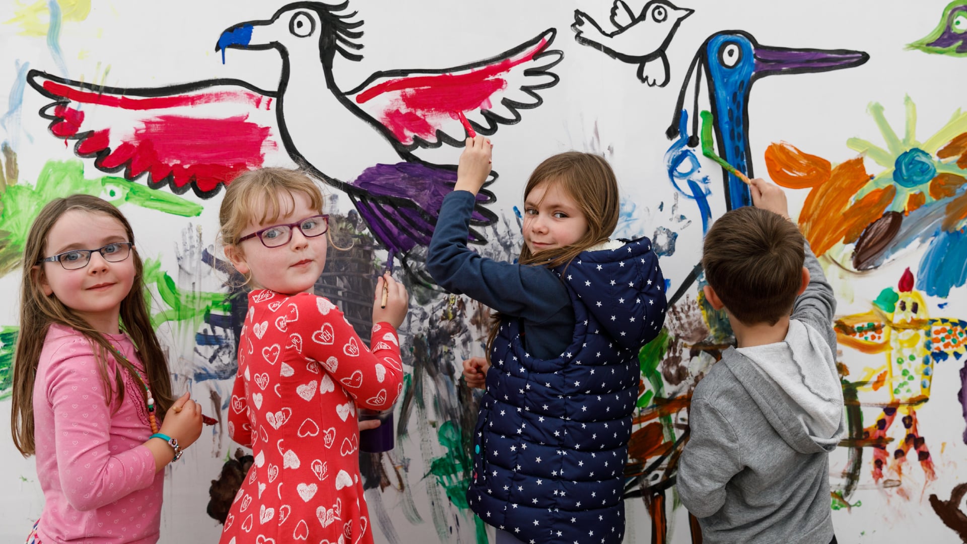 children painting birds onto a big canvas