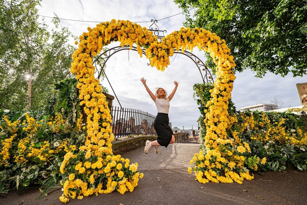 Woman jumping between archway of flowers