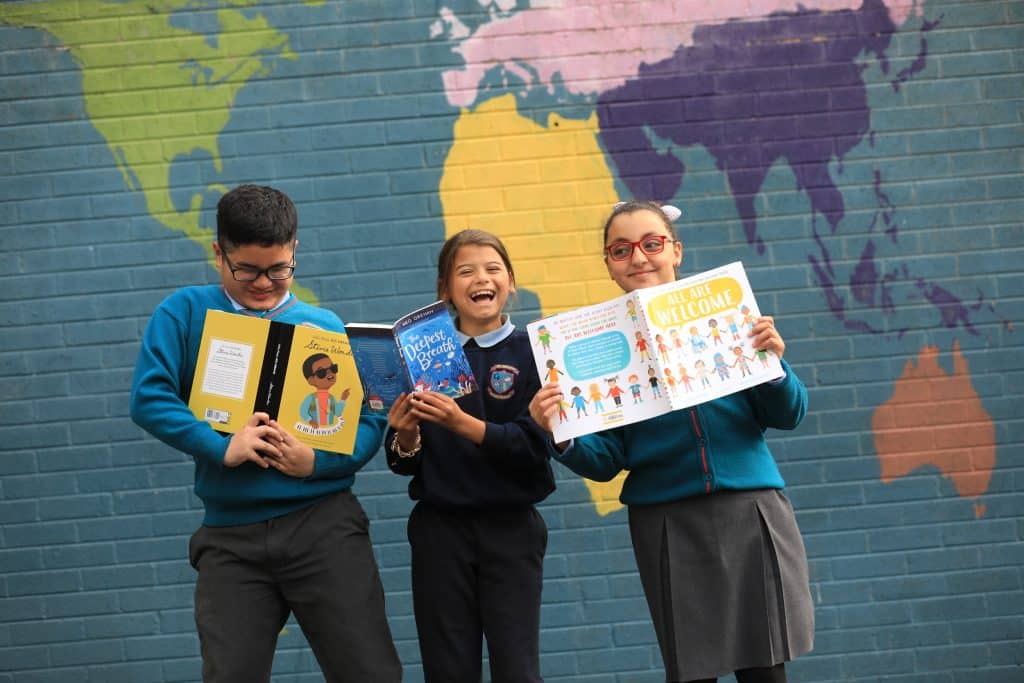 Three Children with books looking joyous