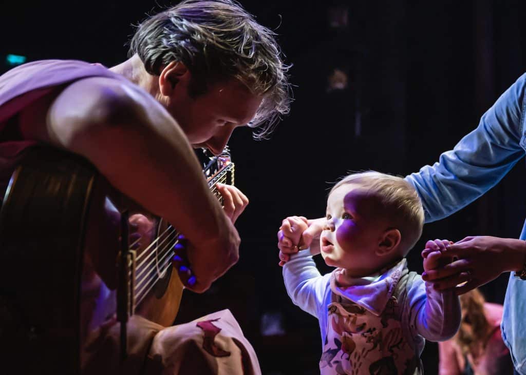 Young child listening to person playing guitar