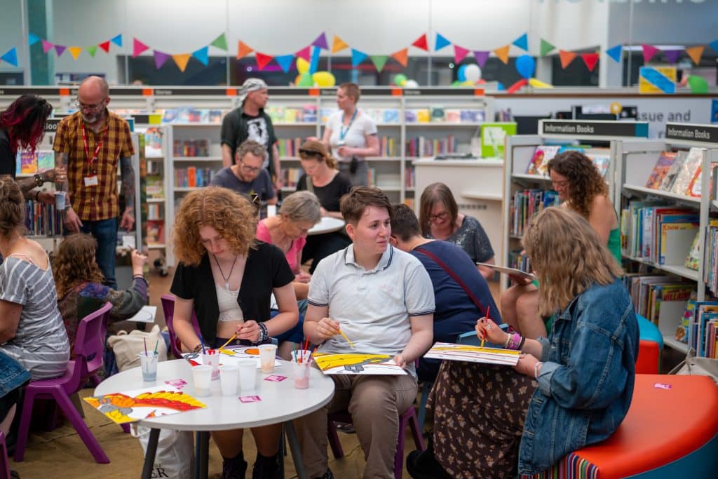 Group of people painting in a library setting