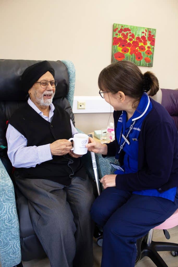 Nurse handing a gentleman an hot drink