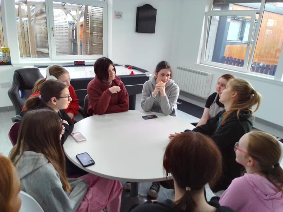 group sitting around a table talking and listening